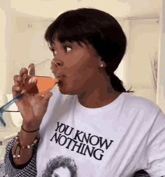 a woman wearing a you know nothing t-shirt is drinking a glass of wine .