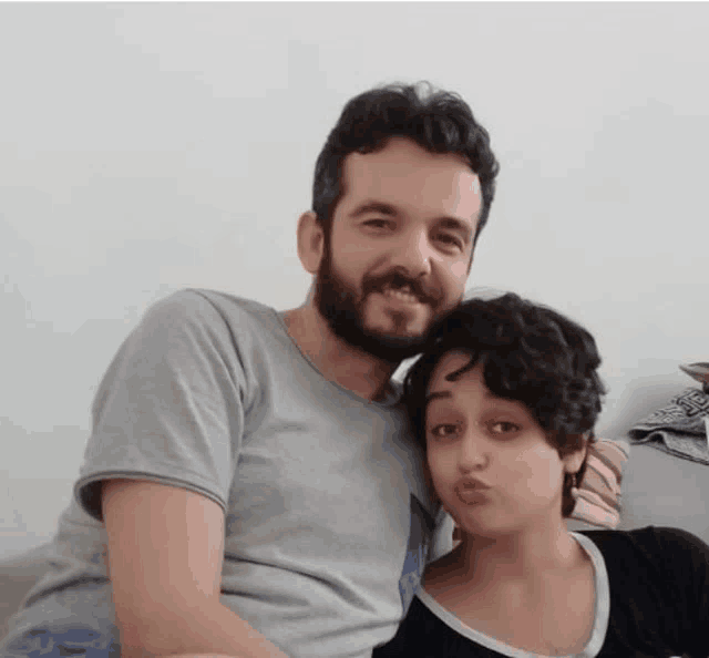 a man and a woman are posing for a picture and the woman is making a funny face