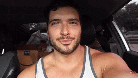 a man in a white tank top is sitting in a car