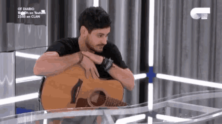 a man is playing an acoustic guitar on a table .