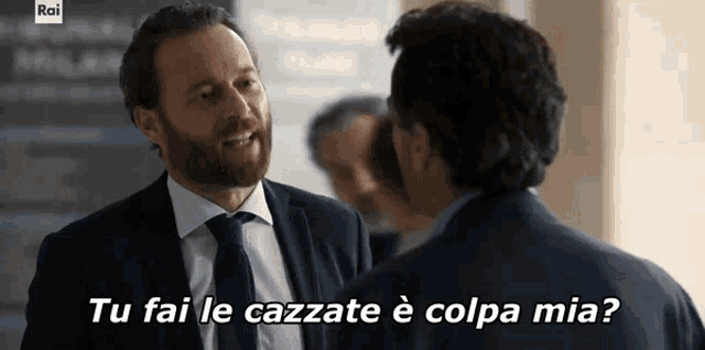 a man in a suit and tie is talking to another man with the caption " tu fai le cazzate è colpa mia "