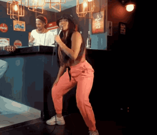 a woman singing into a microphone in front of a sign that says coke