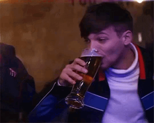 a man is drinking a glass of beer from a glass .
