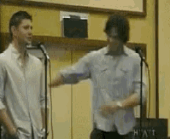 two men are dancing in front of microphones in a room that says hyatt on it