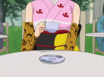 a woman in a kimono sits at a table holding a cup of tea