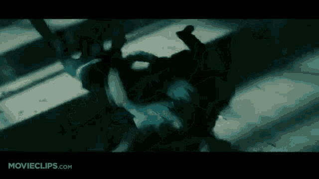 a person is laying on the ground in a dark room with a sword in their hand .