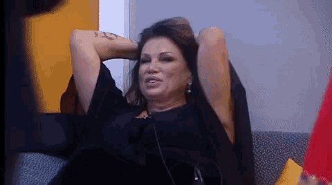 a woman sitting on a couch with her arms behind her head
