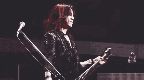 a man is playing a guitar and singing into a microphone on a stage .