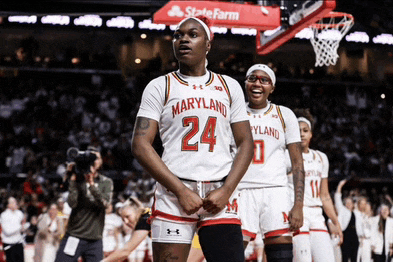 a maryland basketball player stands in front of a state farm sign