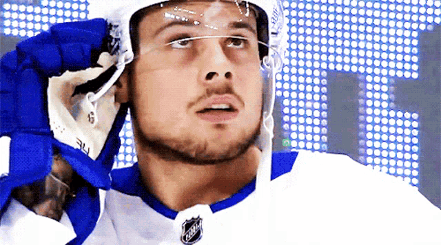 a hockey player wearing a helmet and gloves with the nhl logo on it