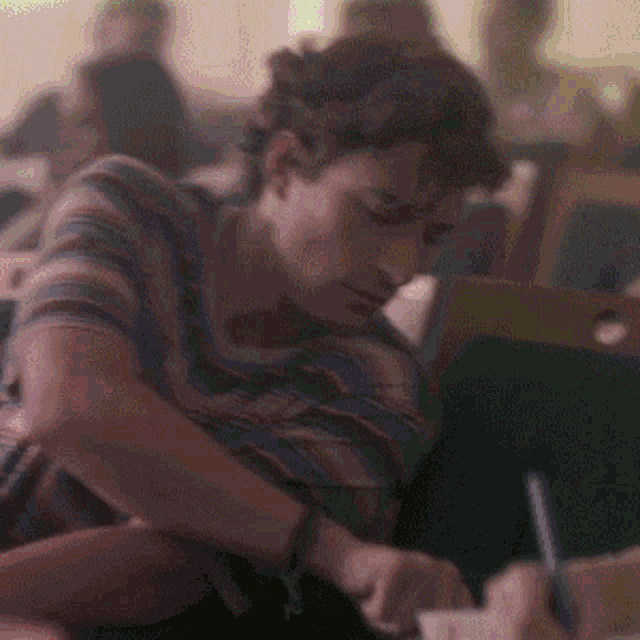 a man is writing on a piece of paper with a pen
