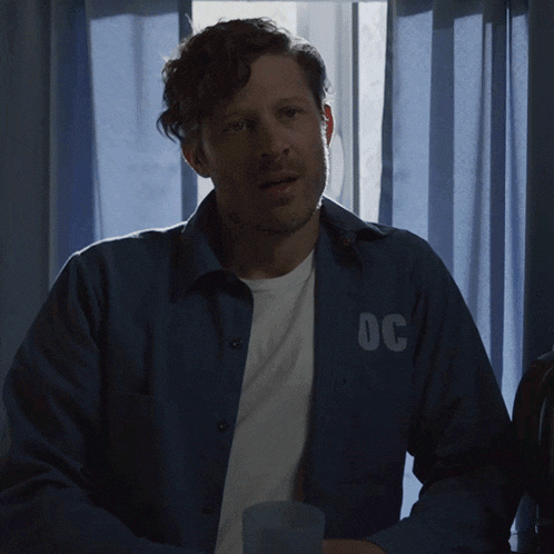 a man wearing a blue shirt with the letters oc on the back