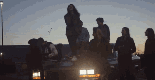 a group of people standing on top of a car with the letter a on the back