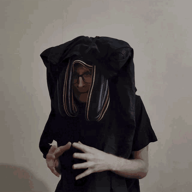 a man wearing glasses and a black shirt with a hood covering his head