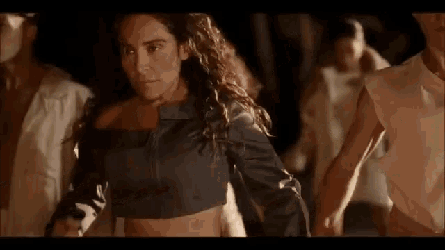 a woman in a crop top is dancing with a group of men .