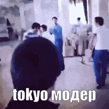 a group of people are standing in a room with the words tokyo modep written on the bottom of the image .
