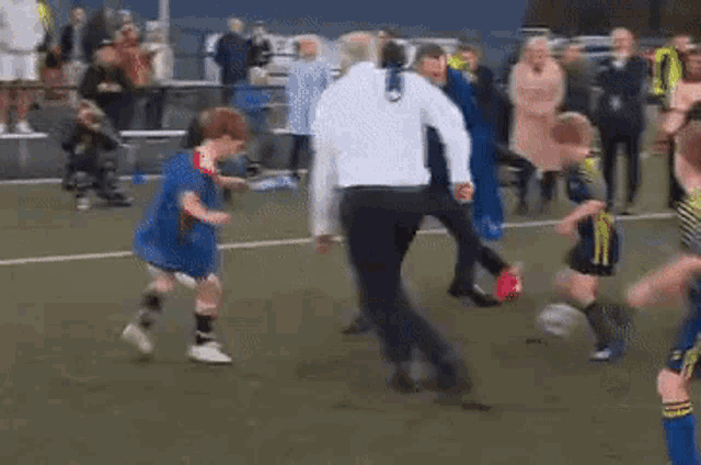 a man in a white shirt is kicking a soccer ball on a field