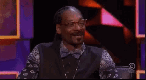 snoop dogg is drinking a glass of wine while sitting in front of a cowboy studios sign