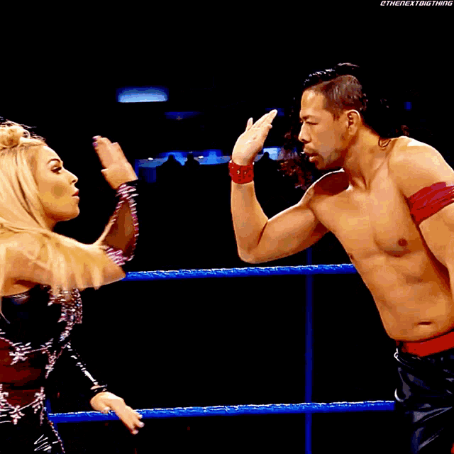 a man and a woman are in a wrestling ring and the woman is wearing a black dress