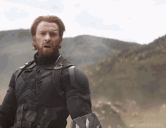 a man in a captain america costume stands in front of a mountain range