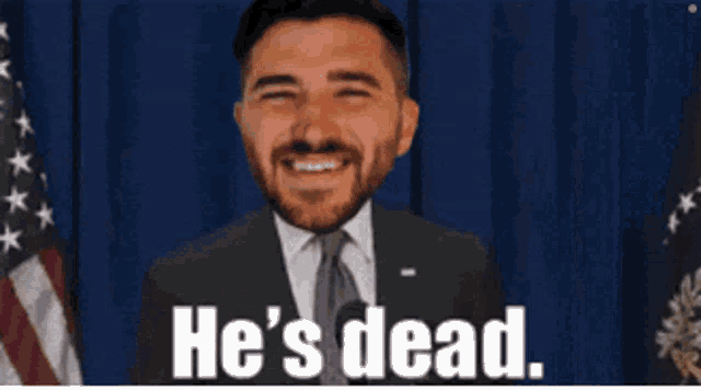 a man in a suit and tie is smiling with the words he 's dead below him