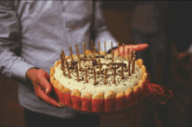 a person holding a cake with candles on it