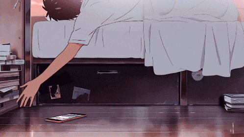 a person laying on a bed reaching for a phone on the floor