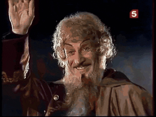 a man with a beard is waving his hand in front of a sign that has the number 5 on it