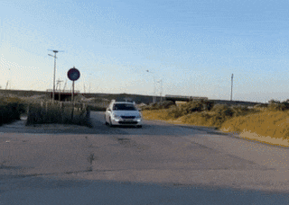 a white car is driving down a road next to a red no entry sign