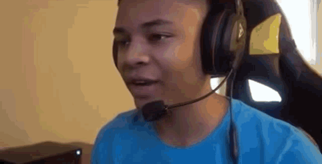 a young man is wearing headphones and a microphone while sitting in a chair .