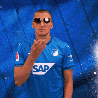 a man wearing sunglasses and a blue shirt that has the word sap on it