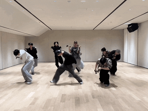 a group of young men are dancing in a large room