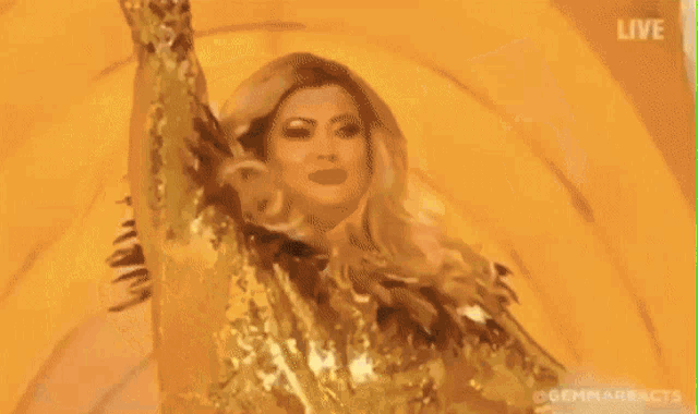 a woman in a gold dress is dancing in front of a yellow background