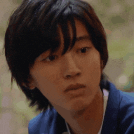 a close up of a young man 's face wearing a blue jacket and looking at the camera .