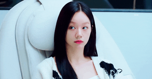 a woman with long black hair is sitting in a white chair looking up .