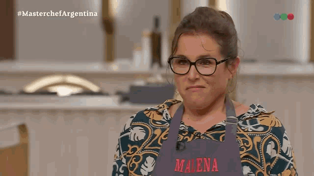 a woman with glasses and an apron that says madena on it