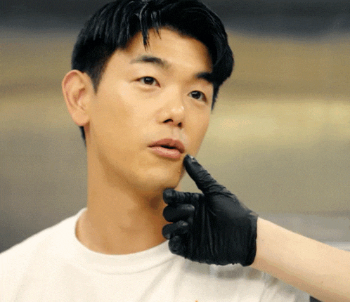 a man wearing a white shirt and black gloves holds his finger to his mouth