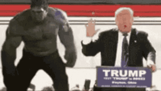a man in a suit and tie stands next to a man in a hulk costume and a trump sign