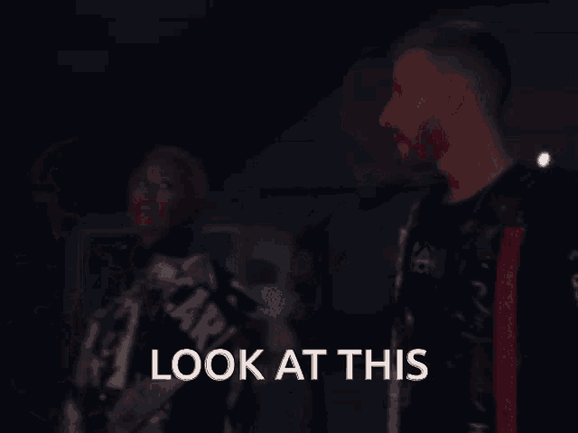 a group of people are standing in a dark room and the words look at this are displayed
