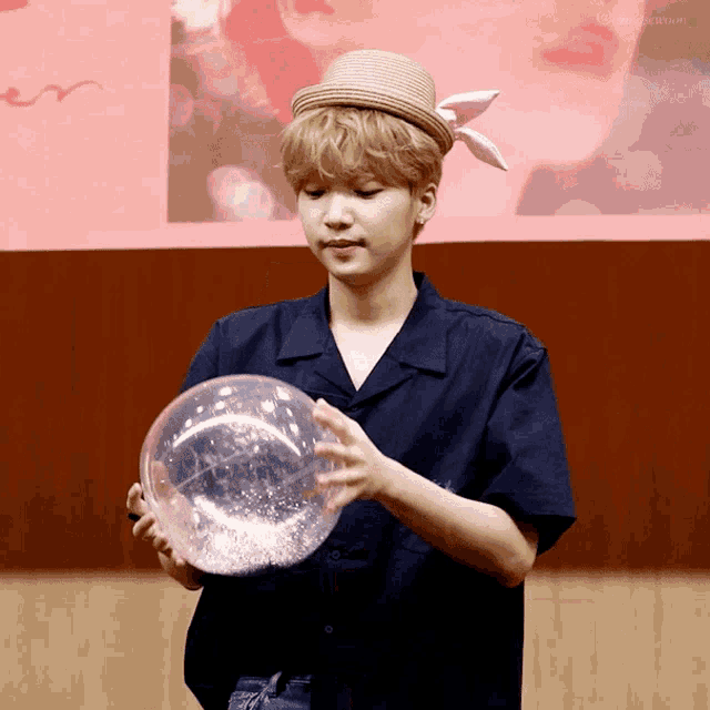 a man in a straw hat holds a clear ball