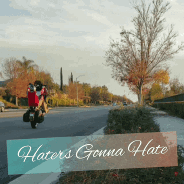 a person riding a motorcycle down a street with the words haters gonna hate above them