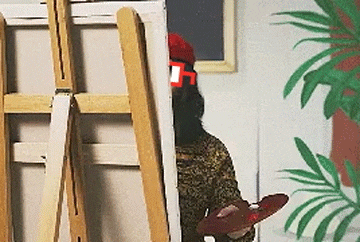 a person is standing in front of an easel holding a brush .