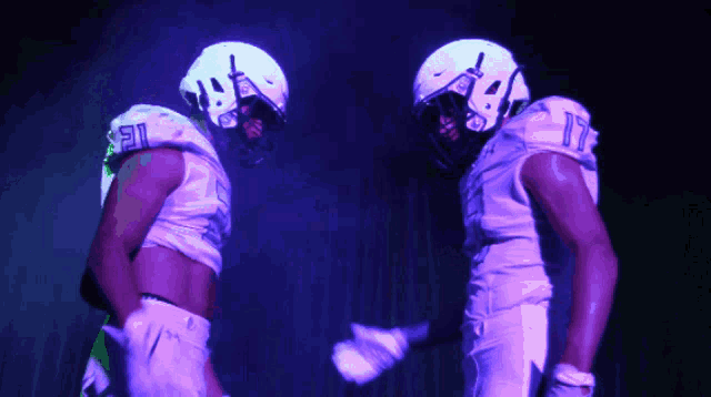 two football players wearing white uniforms with the numbers 21 and 18