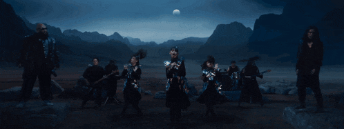 a group of people are standing in front of mountains and a full moon