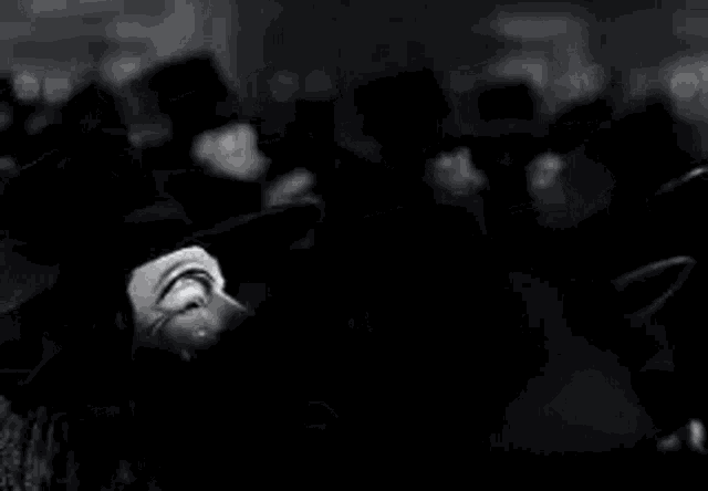 a black and white photo of a group of people wearing anonymous masks .