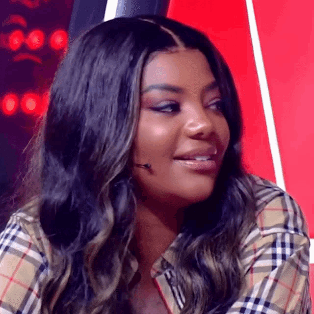 a woman is wearing a plaid shirt and smiling