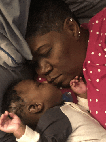 a woman kisses a baby who is sleeping next to her