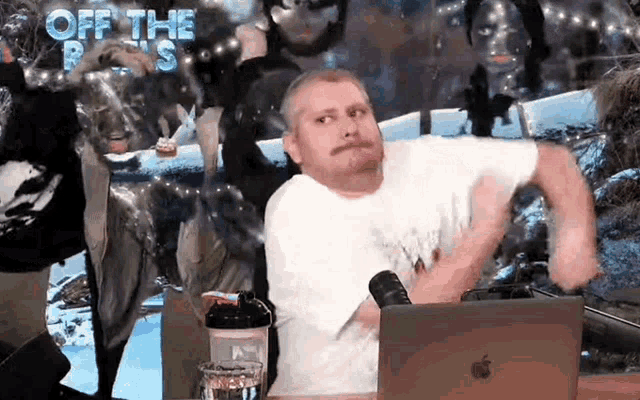 a man with a mustache is sitting in front of a laptop computer .