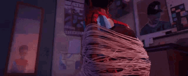 a person in a spiderman costume is wrapped in a spider web .