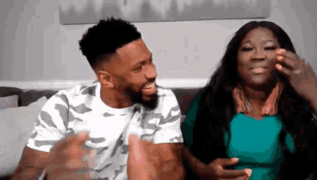 a man and a woman are sitting next to each other on a couch and laughing .